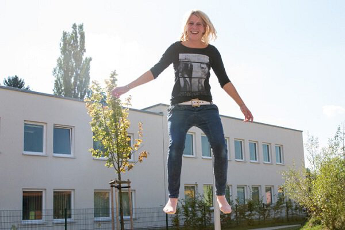 eine pädagogische Fachkraft der Kita Sportforum springt auf dem Boden-Trampolin im Garten der Kita