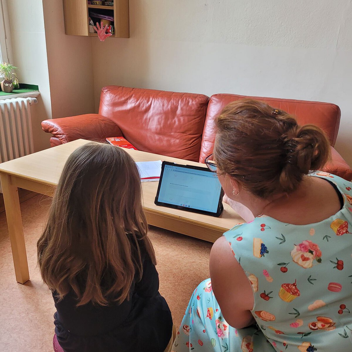 Pädagogische Fachkraft und Kind arbeiten gemeinsam am Tablet der Kita Lowi