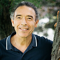 Marco Pena FbS Dresden Lehrkraft Marco Pena vor grünem natürlichen Hintergrund lächelt in die Kamera