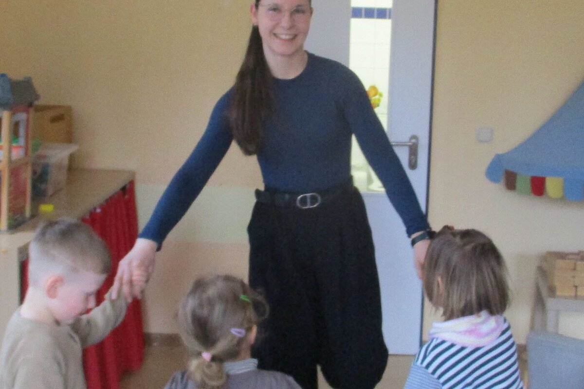 Anerkennunspraktikantin aus der Kita Windischholzhausen tanzt mit den Kindern im Reigen