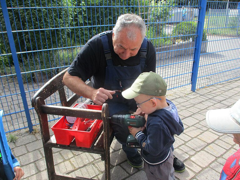 Unterstützung - Hausmeister - Werkeln - Freude - Kindergarten Windischholzhausen Ein Kind unterstützt den Hausmeister beim Bohren