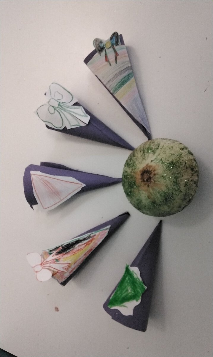 Papierbastelei mit bemalten Elementen rund um eine Kugel