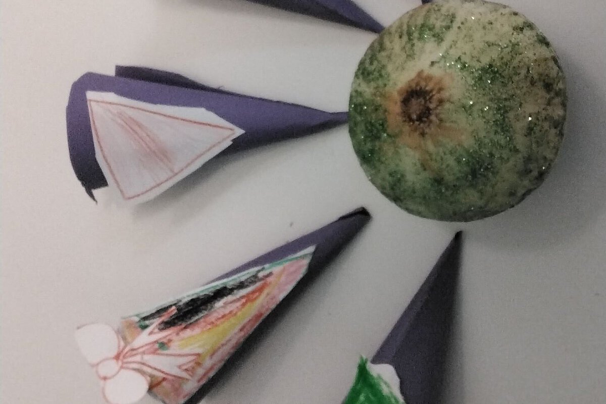 Papierbastelei mit bemalten Elementen rund um eine Kugel