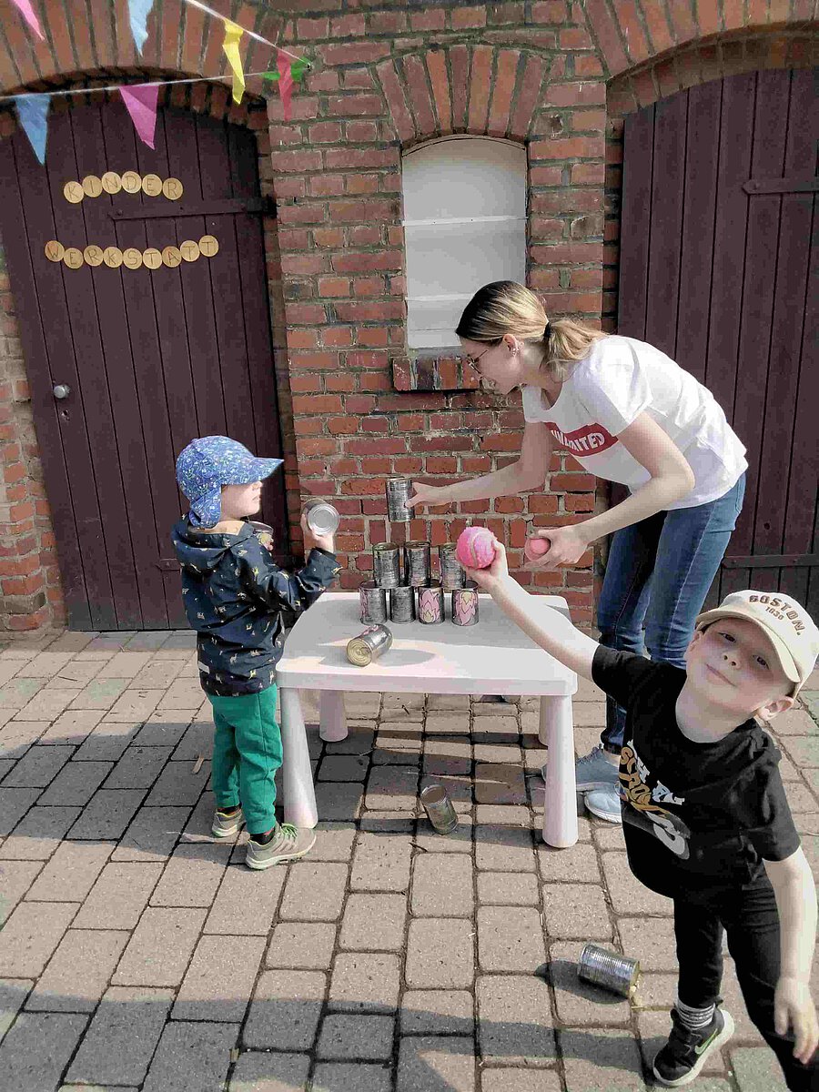 Erzieherin Sophia spielt Dosenwerfen mit den Kindern der Kita Windischholzhausen