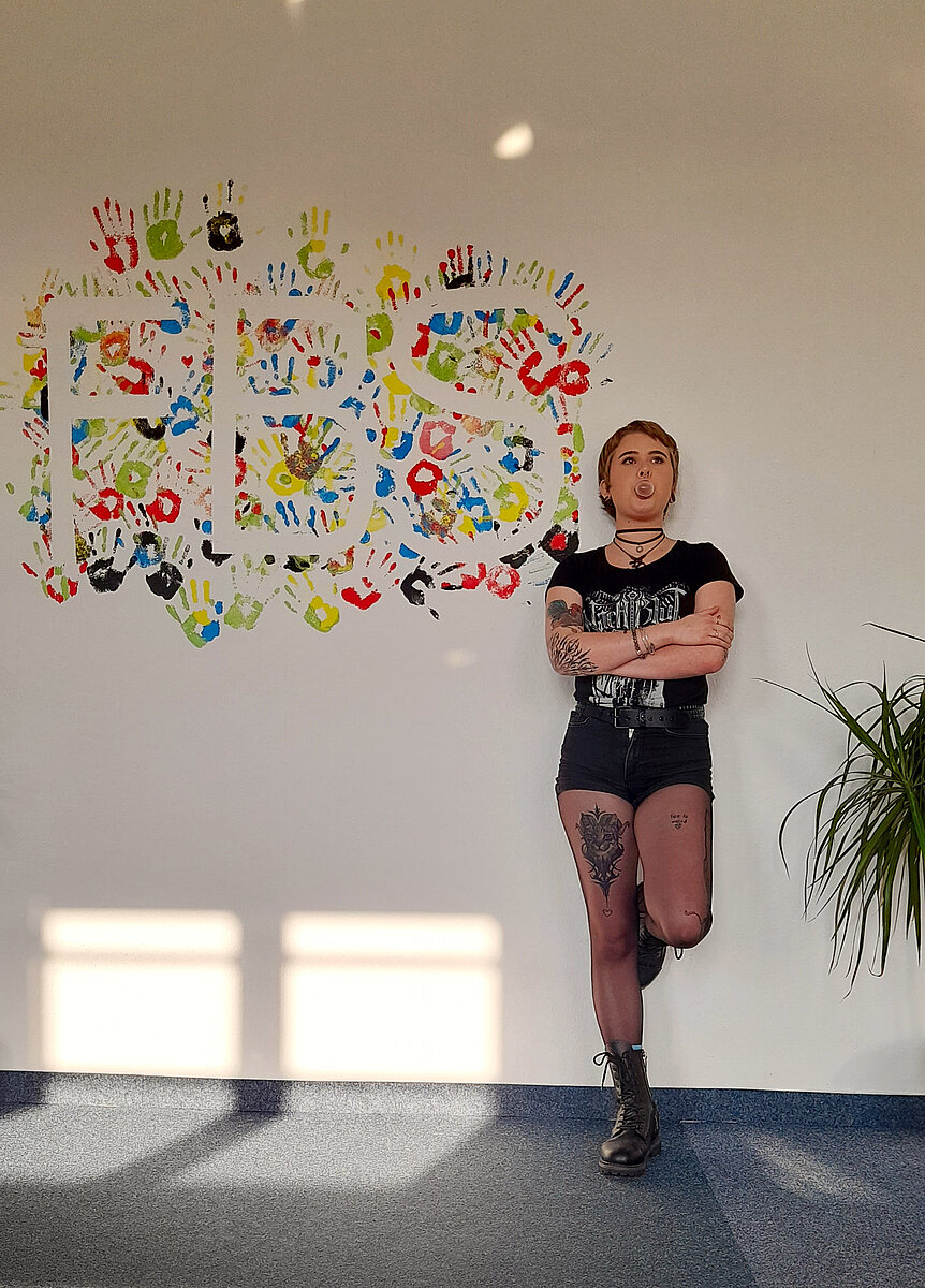 Lena, Auszubildende der FBS Dresden, vor einer Wand mit Handabdrücken
