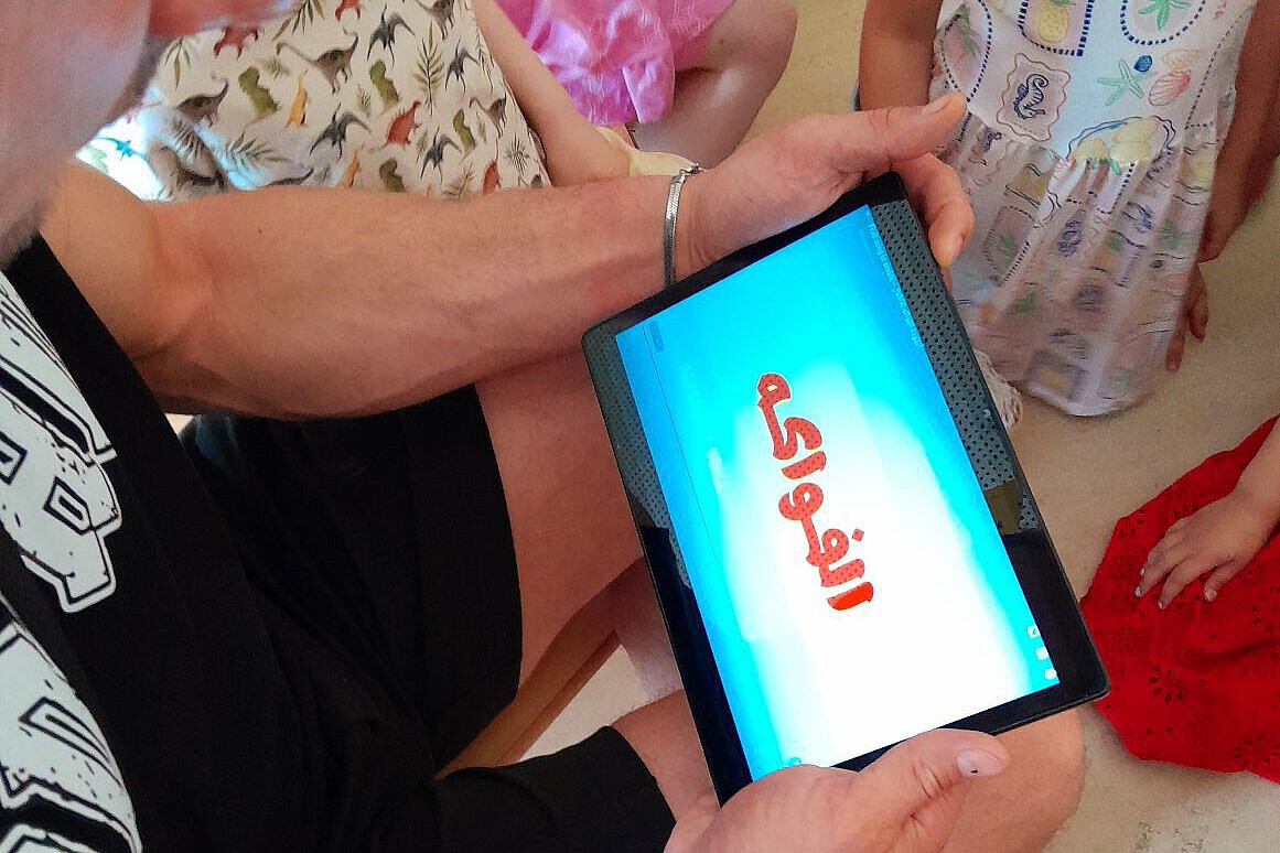 Digitales Lernen in der Kita – Medienpädagogik mit Tablets Pädagogische Fachkraft zeigt Kindern ein Tablet mit digitalem Inhalt im Kita-Alltag