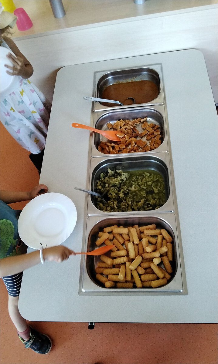 Kinder nehmen sich Essen vom Mittagsbuffet im Kindergarten Wogau