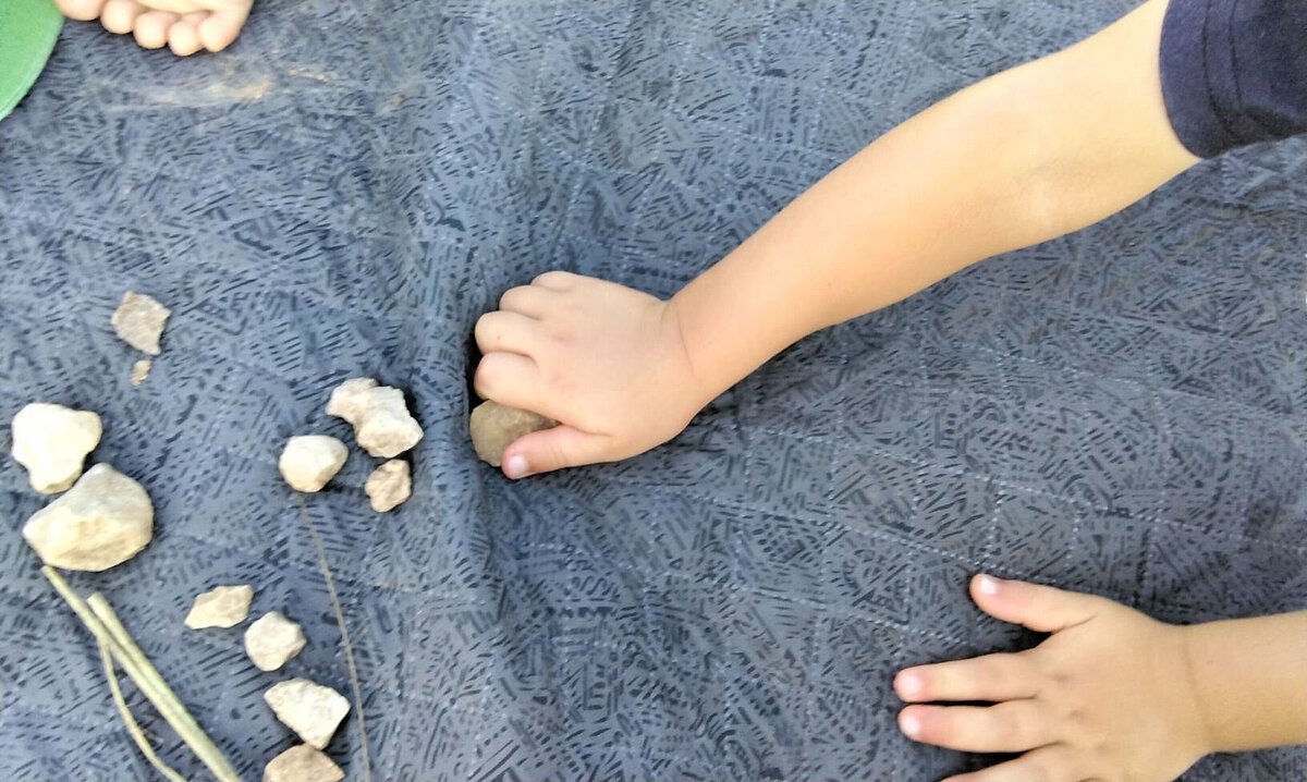 Kinderhände spielen mit kleinen Steinen auf einer Unterlage