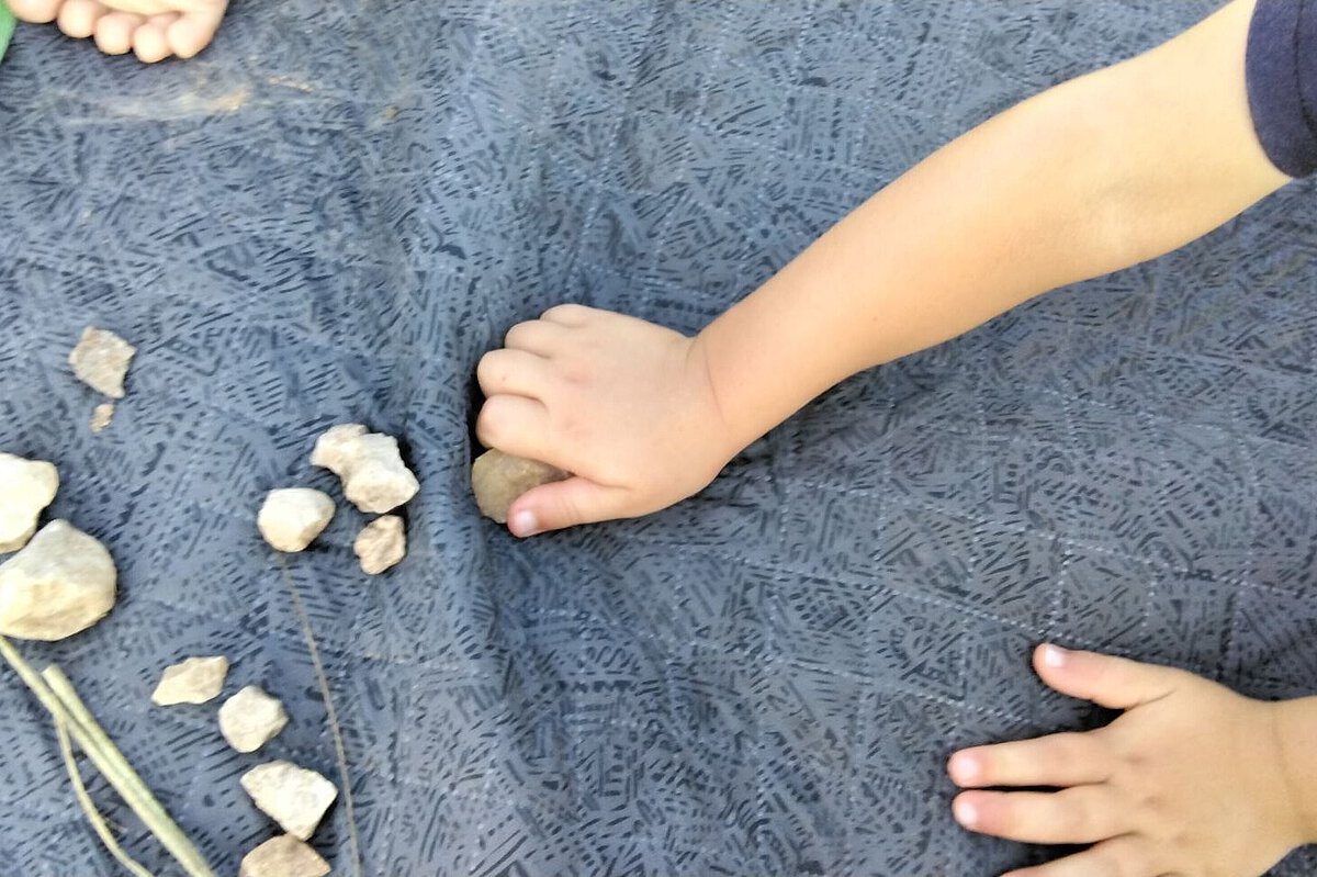 Kinderhände spielen mit kleinen Steinen auf einer Unterlage