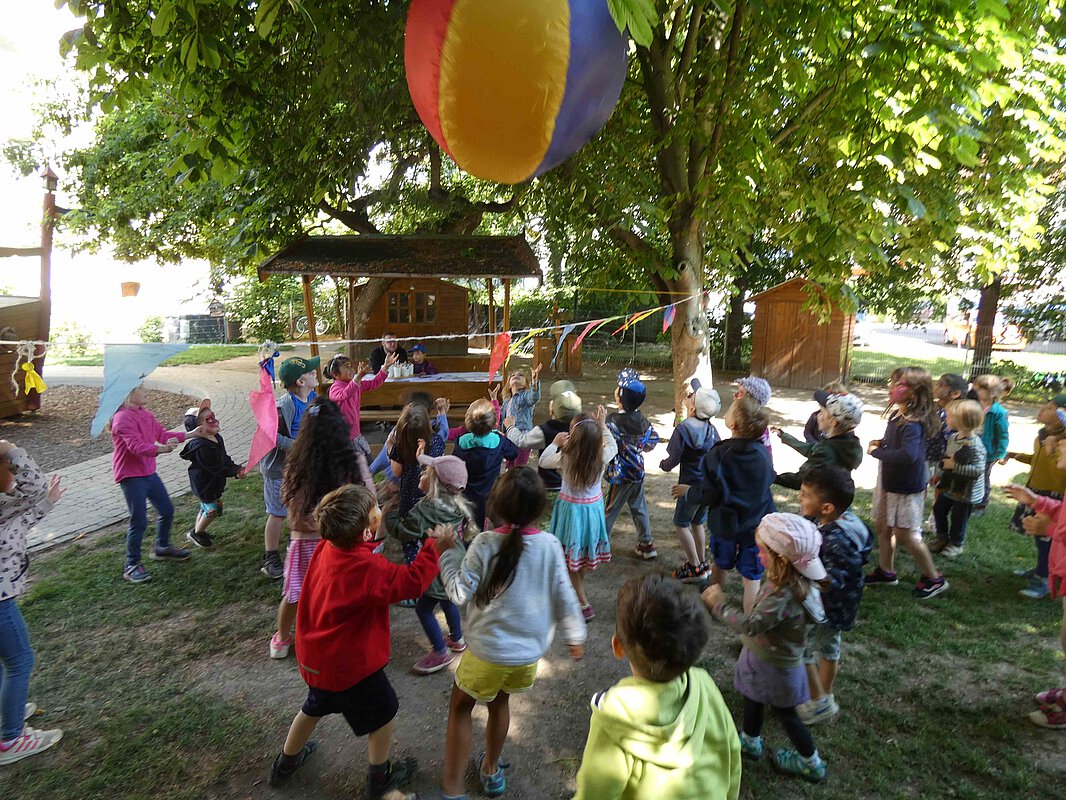 Kinder spielen im Garten mit einem übergroßen Ball