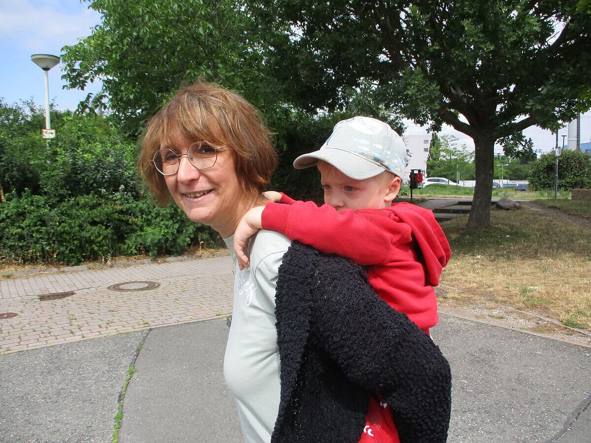 Eine Erzieherin trägt ein Kind huckepack auf dem Weg zum Kindergarten