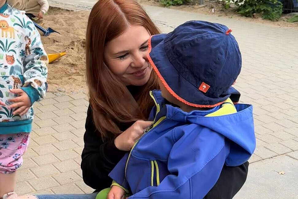 Vertrauensvolle Beziehungen als Grundlage für Resilienz im Kindergarten Am Steiger Eine pädagogische Fachkraft sitzt mit einem Kind im Außenbereich der Kita und widmet ihm ihre ungeteilte Aufmerksamkeit. Verlässliche Beziehungen geben Kindern Sicherheit und stärken ihre emotionale Entwicklung.
