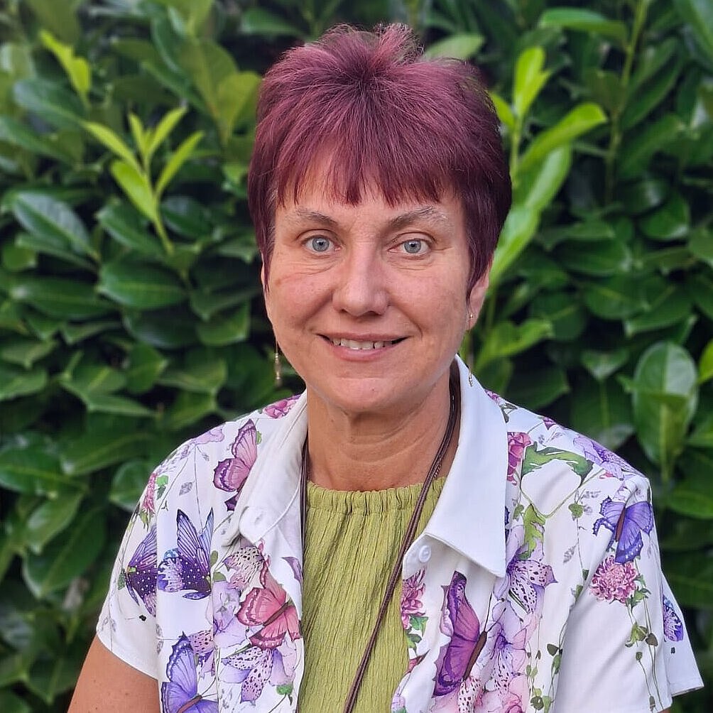 Einrichtungsleiterin des Integrativen Kneipp-Kindergartens Winzerla Heike Morgenbrodt Einrichtungsleiterin Heike Morgenbrodt des Integrativen Kneipp-Kindergartens Winzerla steht vor einem grünen Hintergrund und lächelt in die Kamera.