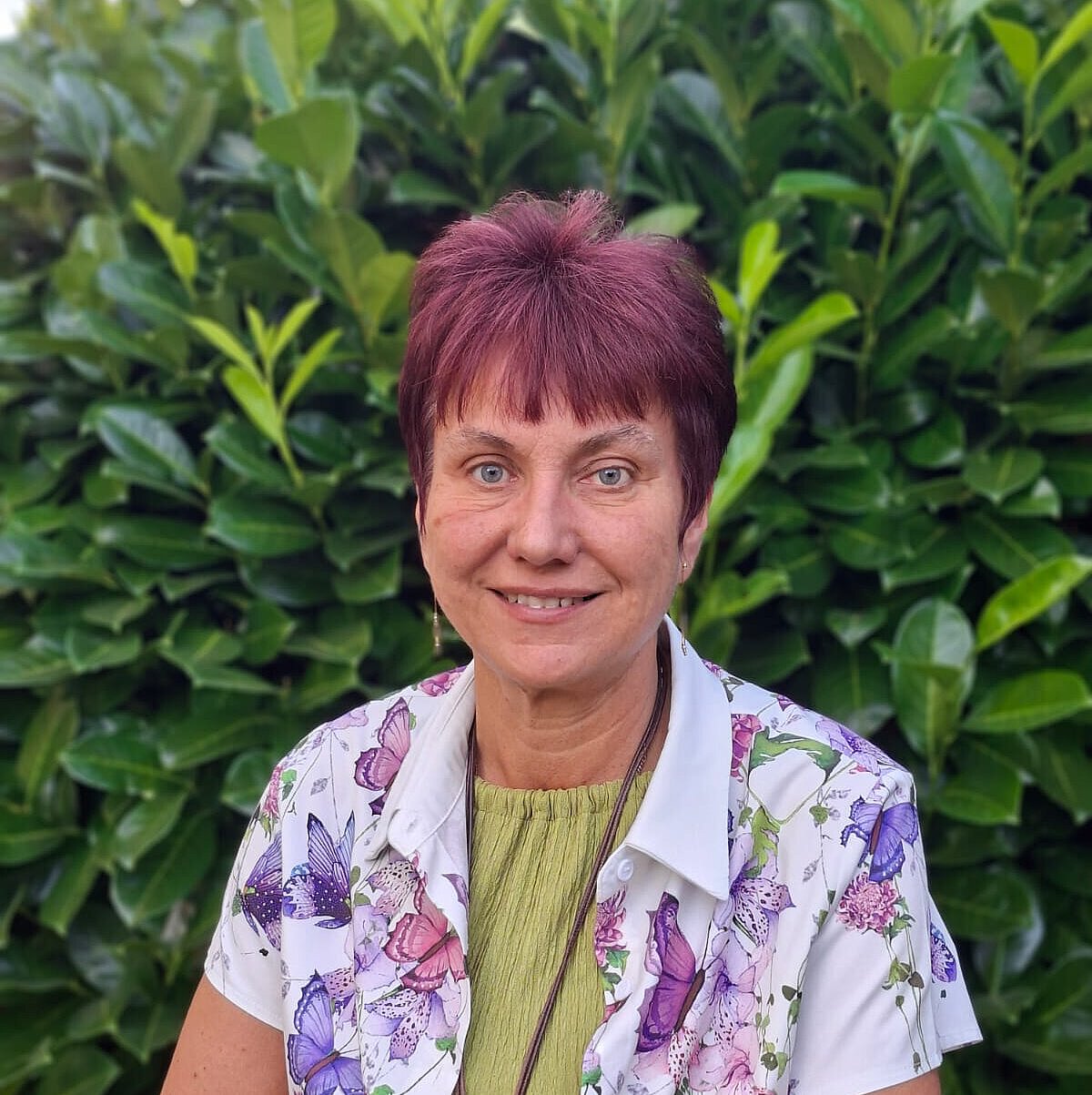 Einrichtungsleiterin des Integrativen Kneipp-Kindergartens Winzerla Heike Morgenbrodt Einrichtungsleiterin Heike Morgenbrodt des Integrativen Kneipp-Kindergartens Winzerla steht vor einem grünen Hintergrund und lächelt in die Kamera.