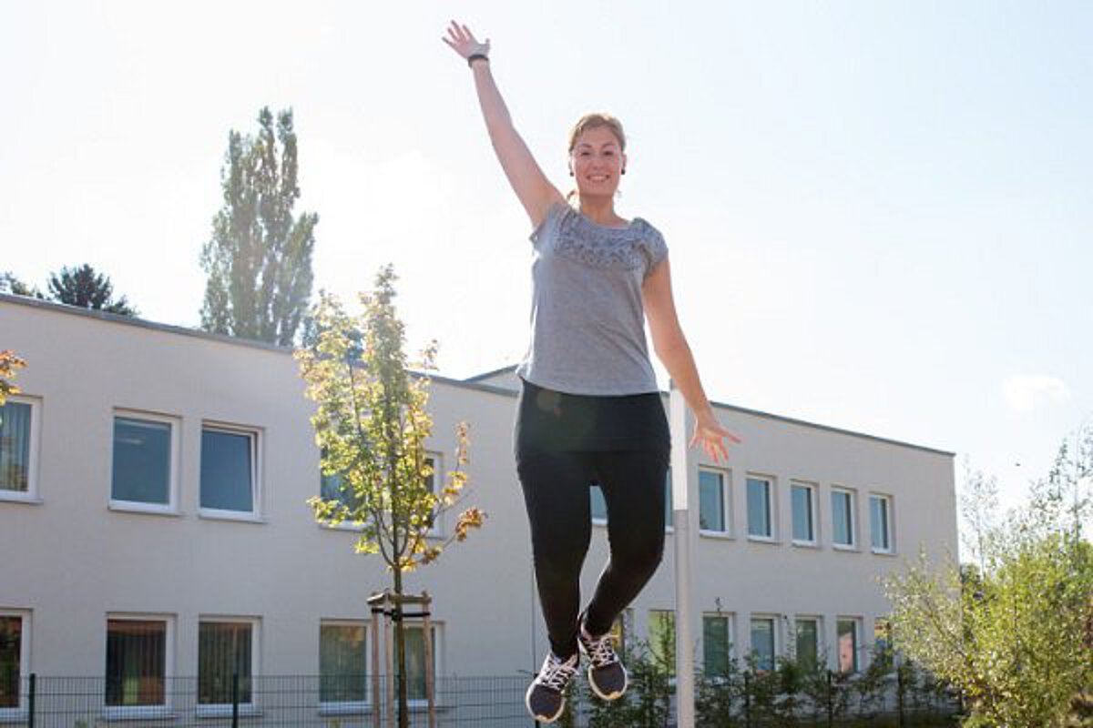 eine pädagogische Fachkraft der Kita Sportforum springt auf dem Boden-Trampolin im Garten der Kita