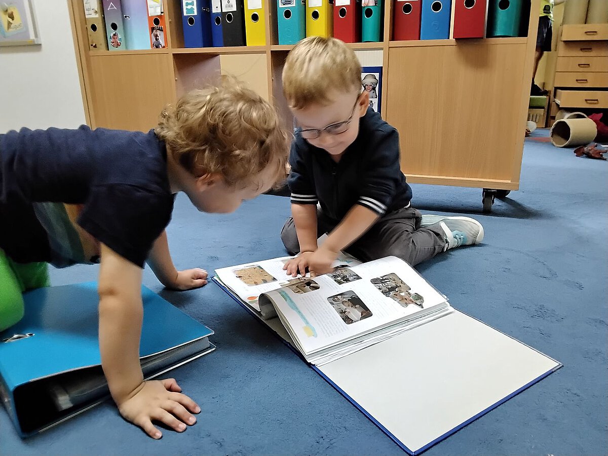 Portfolio - Sprache - Individualität - Kindergarten Windischholzhausen Ein Kind zeigt seinem Freund die Bilder aus seinem Portfolio