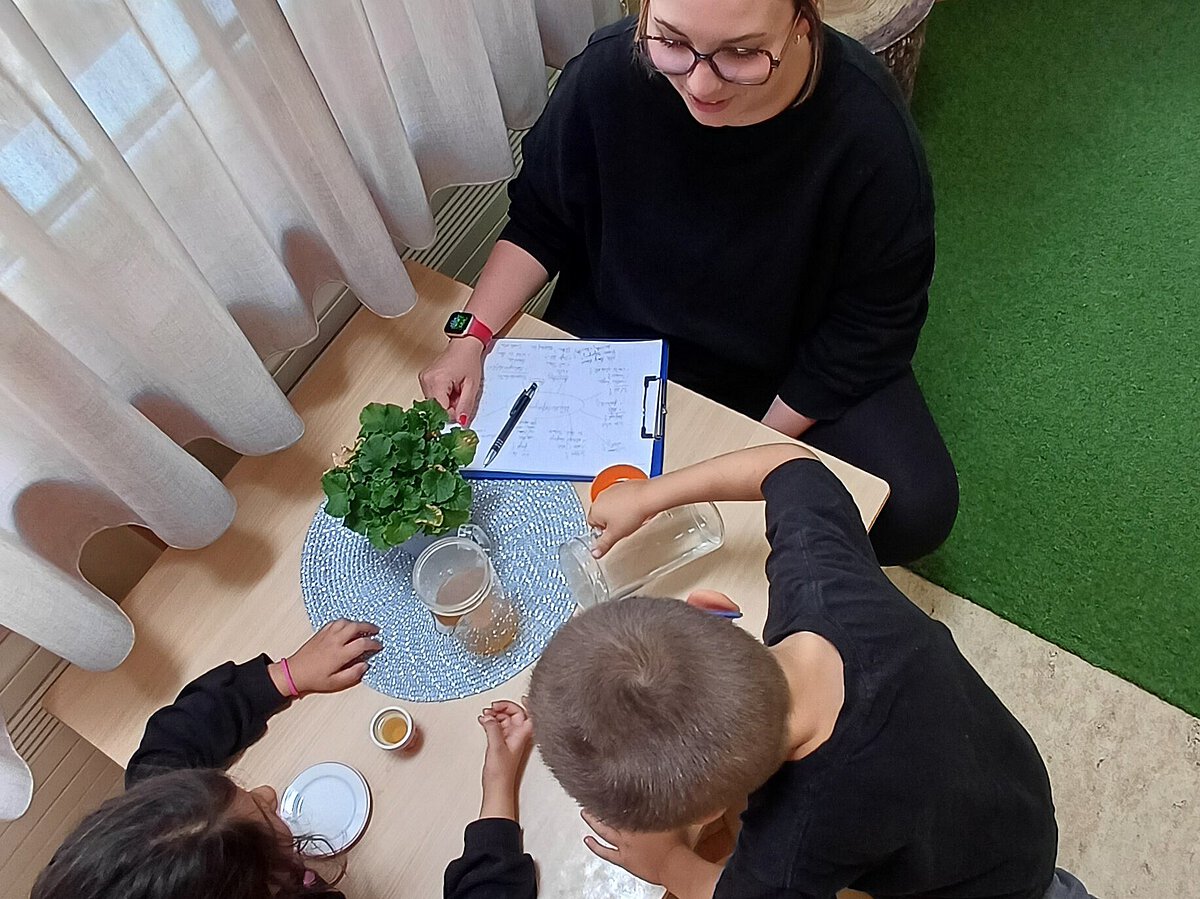 Pädagogische Fachkraft führt ein Interview mit zwei Kindern
