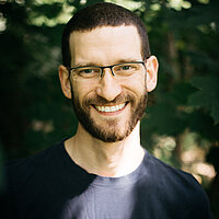 Stefan Feyler FbS Dresden Portraitfoto der Lehrkraft Stefan Feyler der Freien berufsbildenden Schule Dresden vor grünem, natürlichen Hintergrund