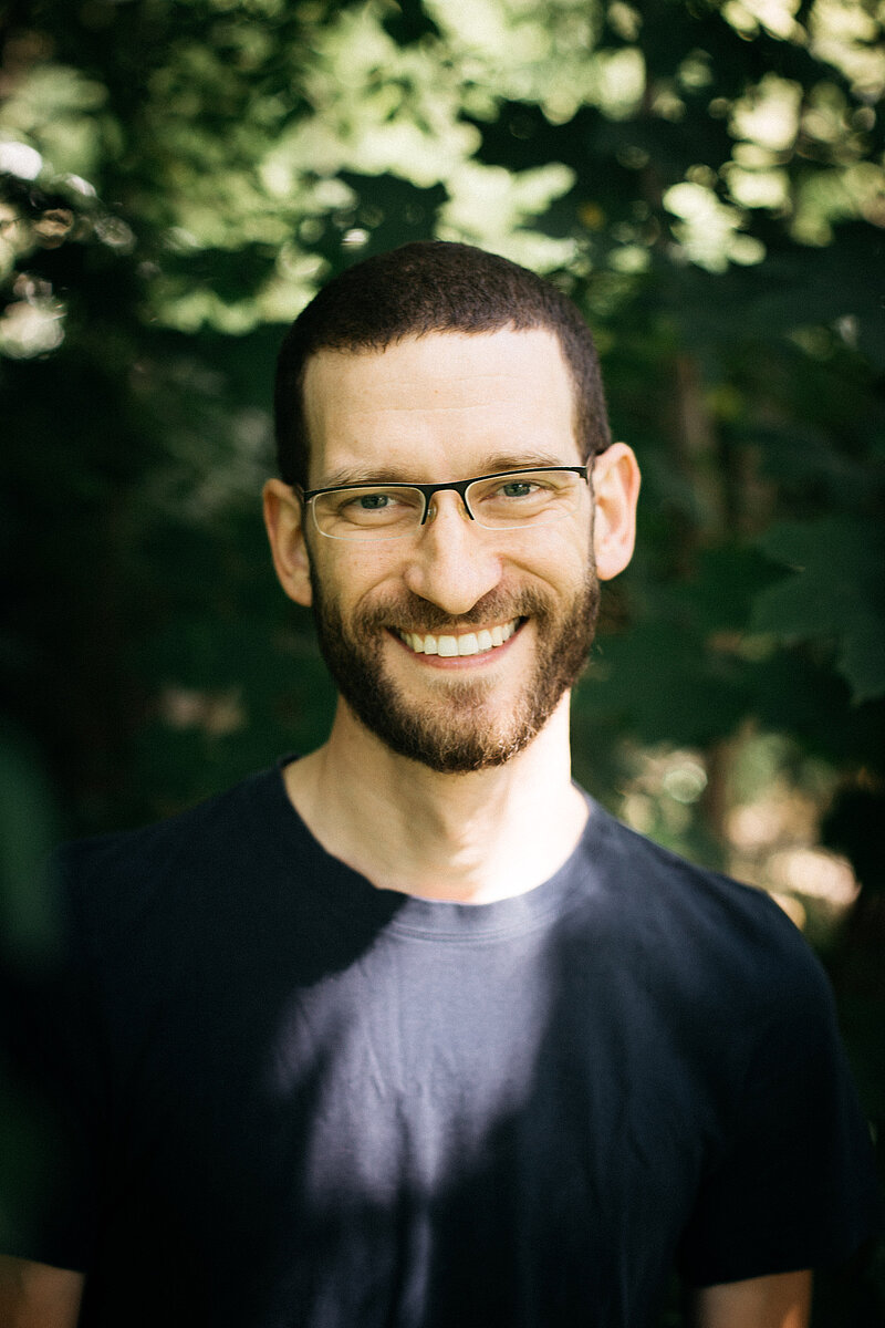 Portraitfoto der Lehrkraft Stefan Feyler der Freien berufsbildenden Schule Dresden vor grünem, natürlichen Hintergrund