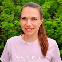 Portrait Einrichtungsleitung Kindertagesstätte Schilfweg Tina Thiel vor grünem natürlichen Hintergrund