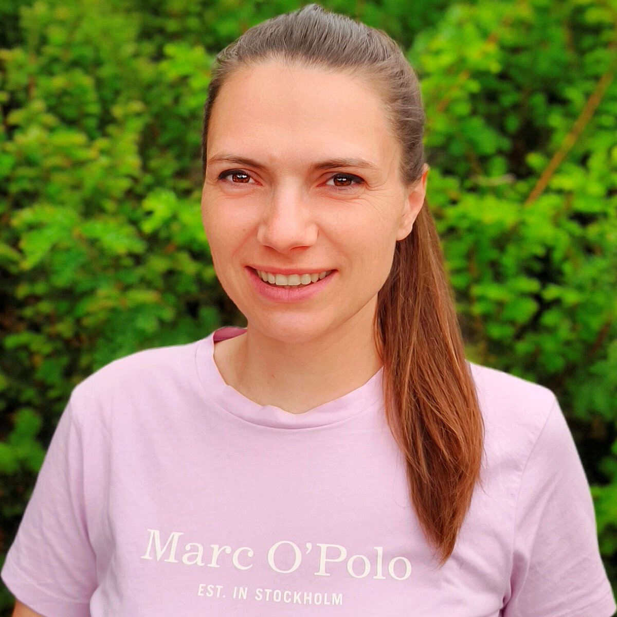 Einrichtungsleitung Kindertagesstätte Schilfweg Tina Thiel Portrait Einrichtungsleitung Kindertagesstätte Schilfweg Tina Thiel vor grünem natürlichen Hintergrund