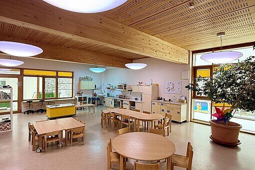 Helles Restaurant in der Kita Sportforum Großer, freundlicher Kita-Raum mit Holzmöbeln, Bastel- und Spielebereichen sowie großen Fenstern mit Blick nach draußen.