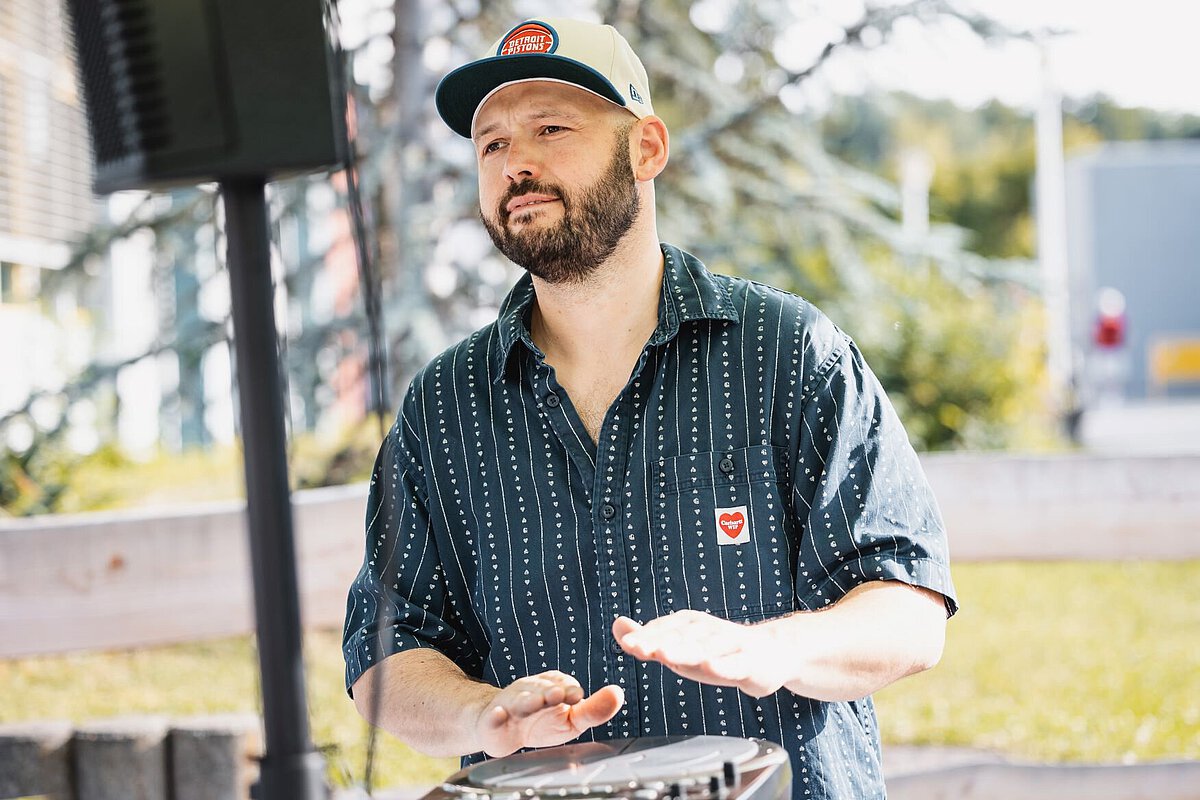 DJ Beatklops im Freien mit Lautsprecher im Hintergrund.
