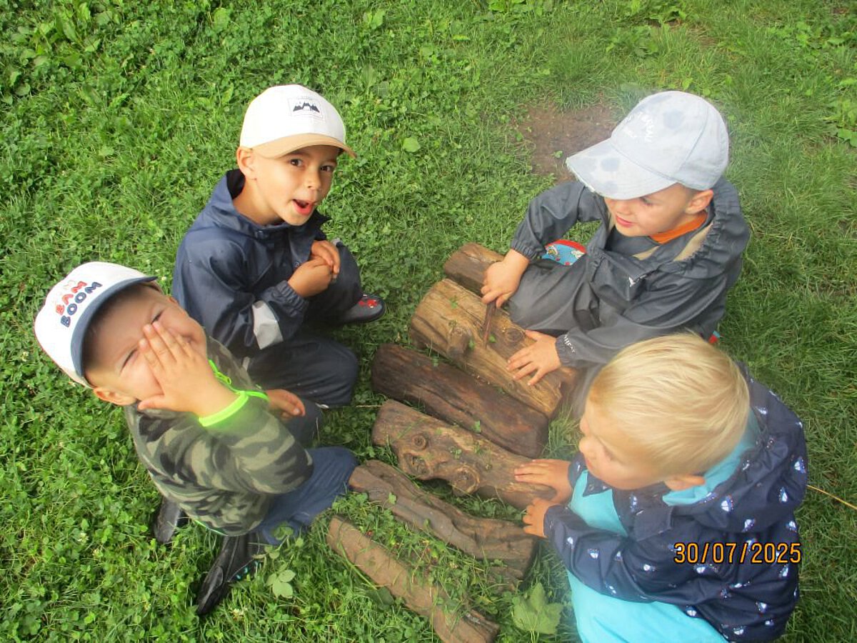 Vier Kinder legen Holzscheite nebeneinander