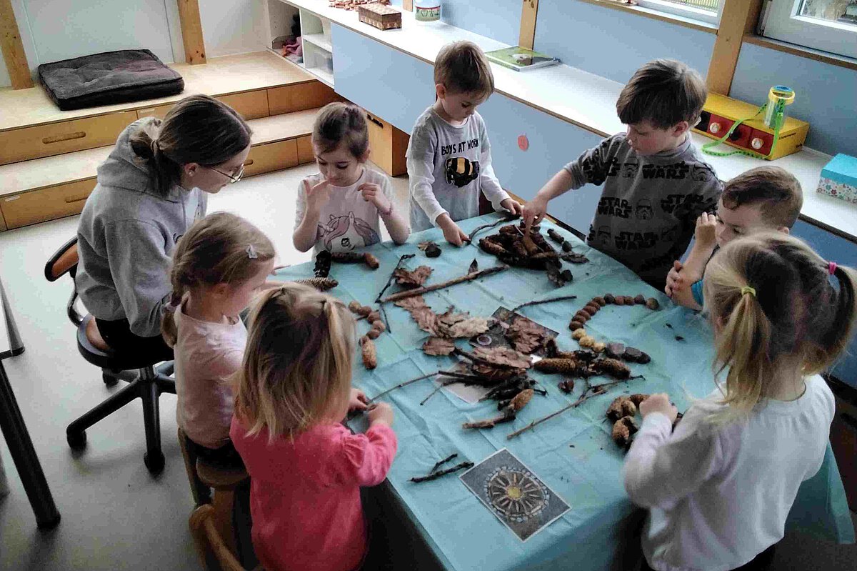 Erzieherin Sophia bastelt mit den Kindern mit Naturmaterialien