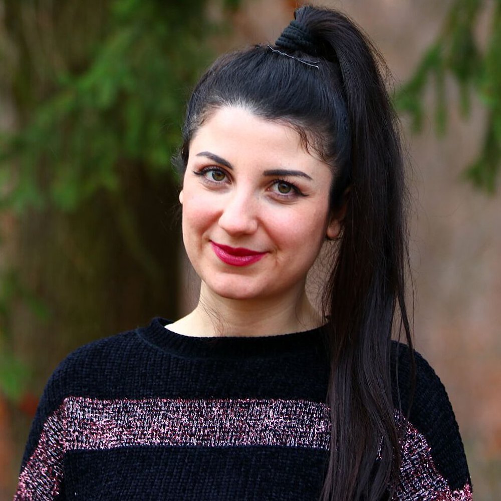 Frau im schwarzen Shirt vor Bäumen