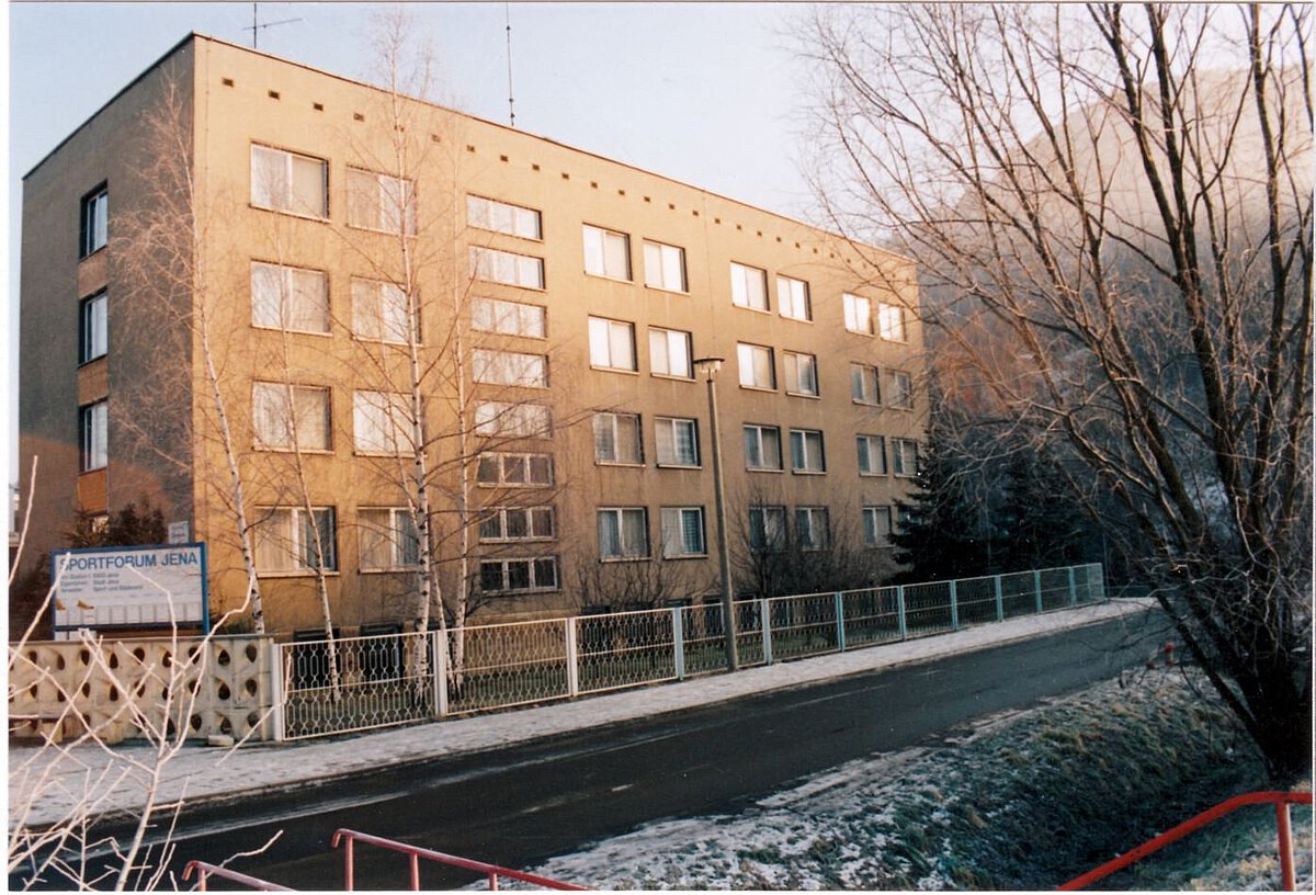 Mehrstöckiges Gebäude des Sportforums Jena im Winter 1995 mit Straßenansicht, kahlen Bäumen und leichter Schneeschicht