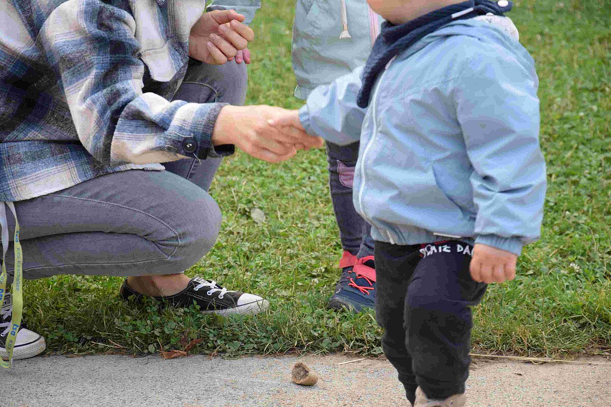 Erzieherin hält die Hand eines Kindes, Begleiterin des Kindes