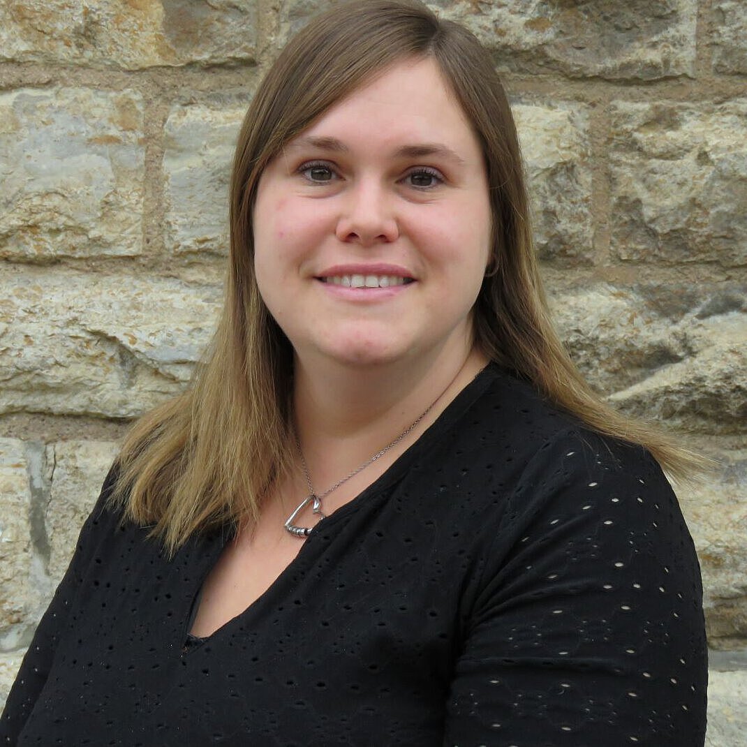 Nancy Thümer Kindergartenleitung Einrichtungsleitung Kindergarten Windischholzhausen Nancy Thümer im schwarzen Oberteil vor einer Steinmauer
