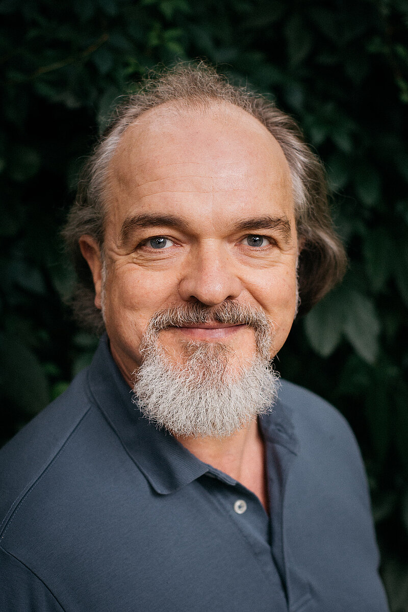 Portrait der Lehrkraft Lutz Knöschke vor einem grünen, natürlichen Hintergrund 