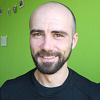 Philipp Bräunig FbS Dresden Lehrkraft Philipp Bräunig vor grünem Hintergrund lächelt in die Kamera