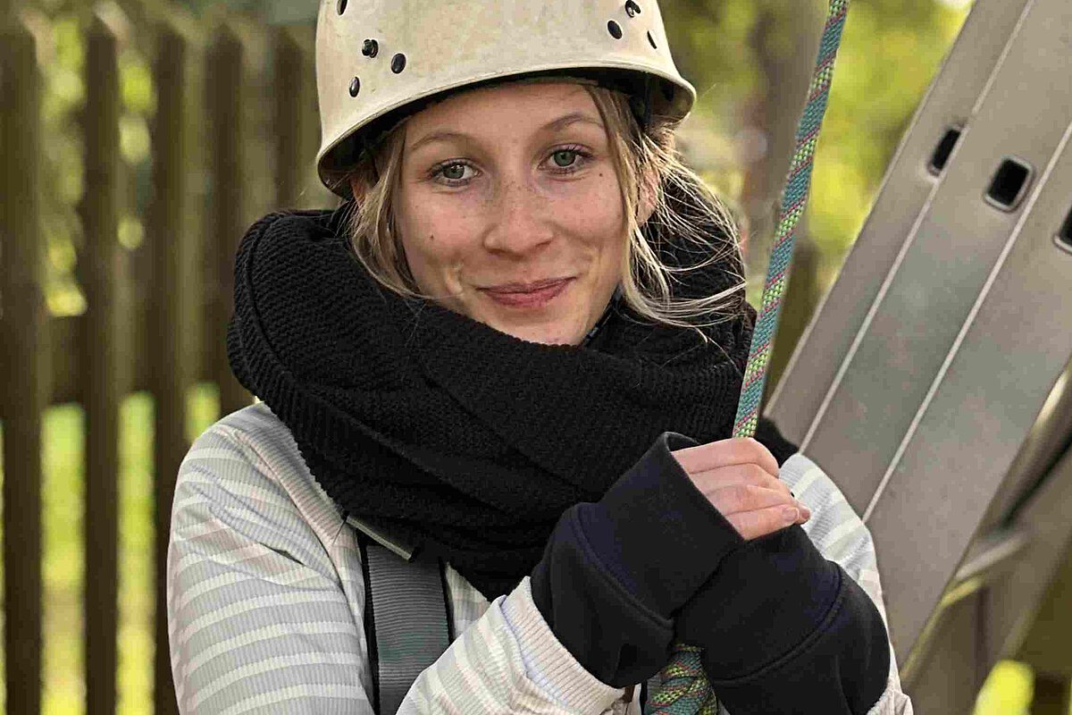 Aufstieg starten an der FBS Jena erson mit Schutzhelm und Sicherungsgurt beim Klettertraining im Außenbereich