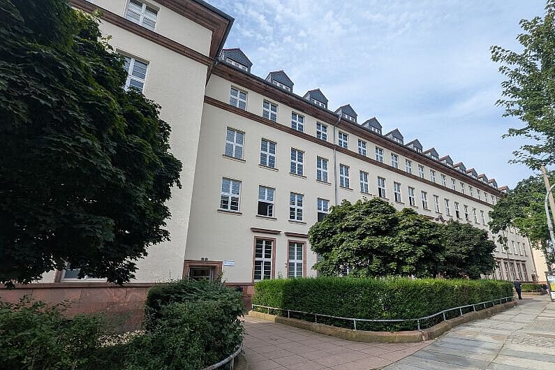 Gebäudeansicht der Freien berufsbildenden Schule Dresden mit viel Grün, zu sehen ist der Vordereingang des Gebäudes.