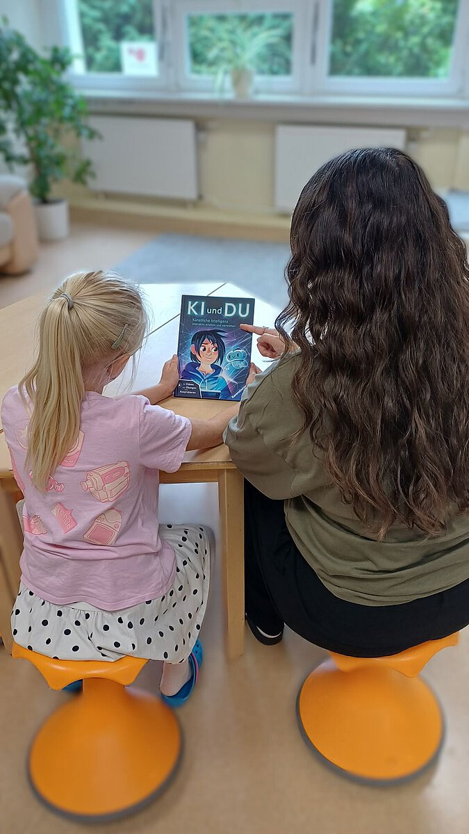 Kinder sitzen gemeinsam an einem Tisch und beschäftigen sich mit dem Bildungsbuch „KI und DU“ zum Thema Künstliche Intelligenz.