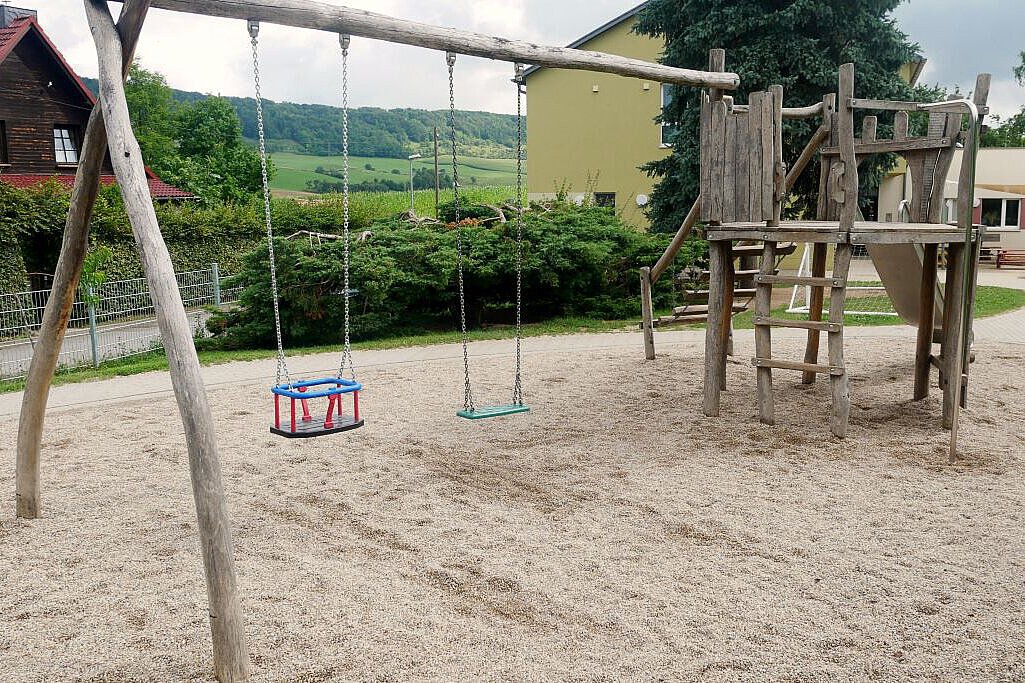 Holzschaukel und Klettergerüst auf dem Spielplatz des Kindergartens Wogau