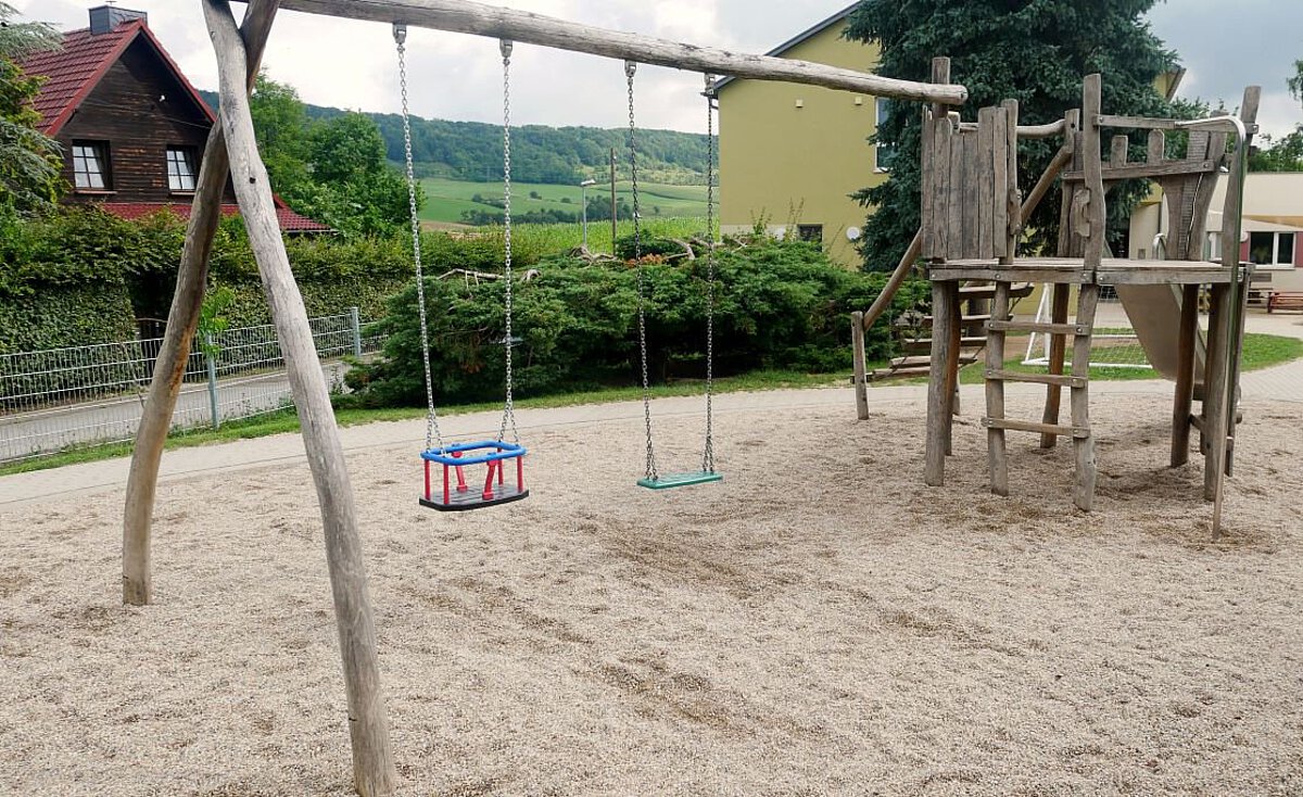 Holzschaukel und Klettergerüst auf dem Spielplatz des Kindergartens Wogau