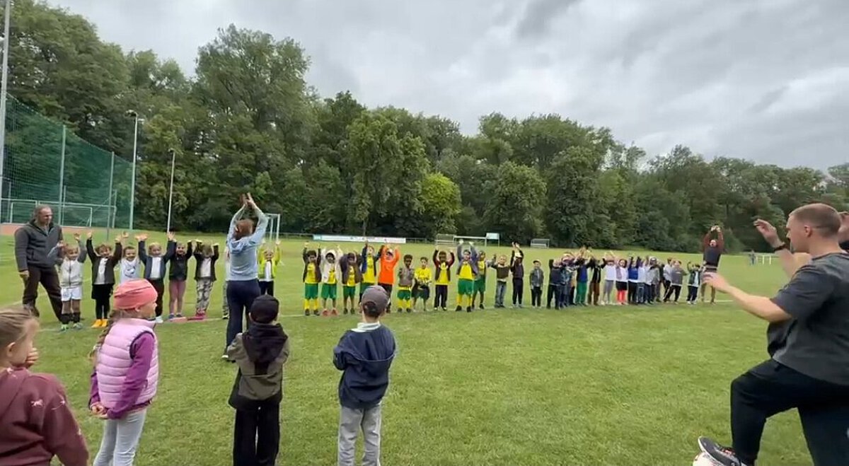 Kinder und Fachkräfte beim gemeinsamen Aufwärmen auf dem Sportplatz beim TSA Fußball-Cup in Vieselbach