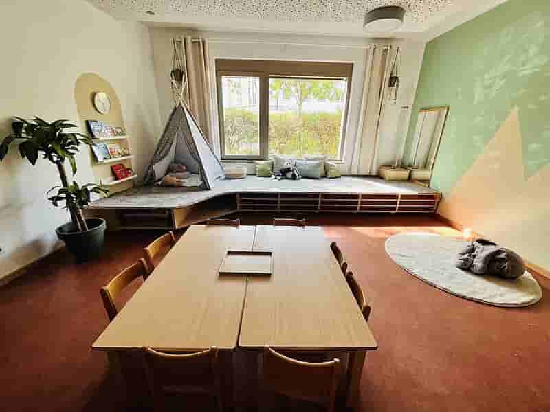 Ruheinsel im Krippenbereich – Rückzugsort für Entspannung und Geborgenheit Gemütliche Ruheinsel im Krippenbereich mit niedrigen Holzmöbeln, Sitzkissen, Pflanzen und weichem Licht für entspannte Momente