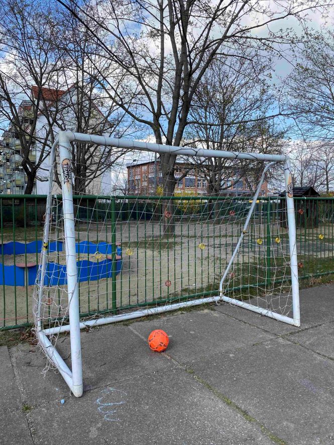 Fußballtor mit Ball auf dem Außengelände des Kindergartens Vollbrachtfinken, im Hintergrund Sandkasten und Zaun.