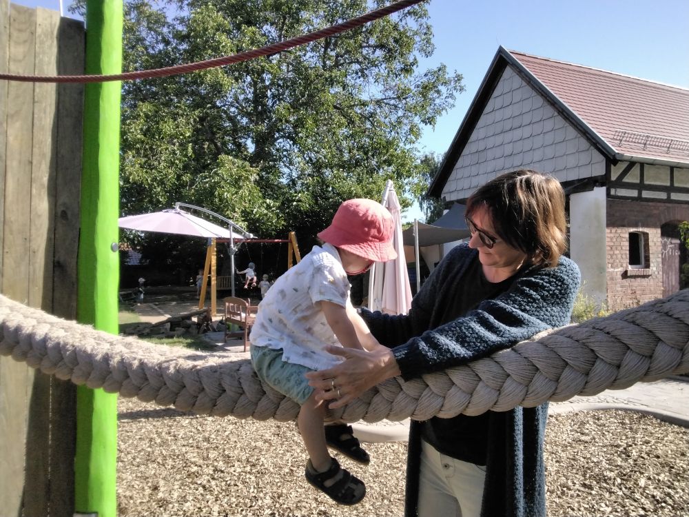 Klettern - Unterstützung - Bewegung - Kindergarten Windischholzhausen Eine Erzieherin hilft einem jüngeren Kind beim Klettern