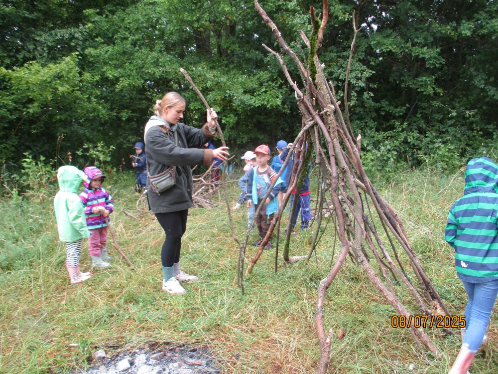 Gemeinsam mit einer Erzieherin bauen die Kinder ein Tipi
