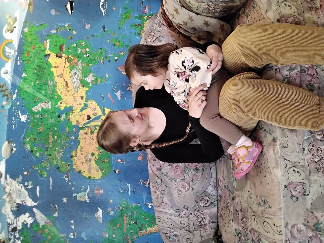 Erzieherin-Kind-Bindung - Interaktion - Eingewöhnung - Liebevoll - Kindergarten Windischholzhausen Eine Erzieherin sitzt auf der Couch mit einem Kind auf dem Schoß und sie sind gerade in einer Unterhaltung