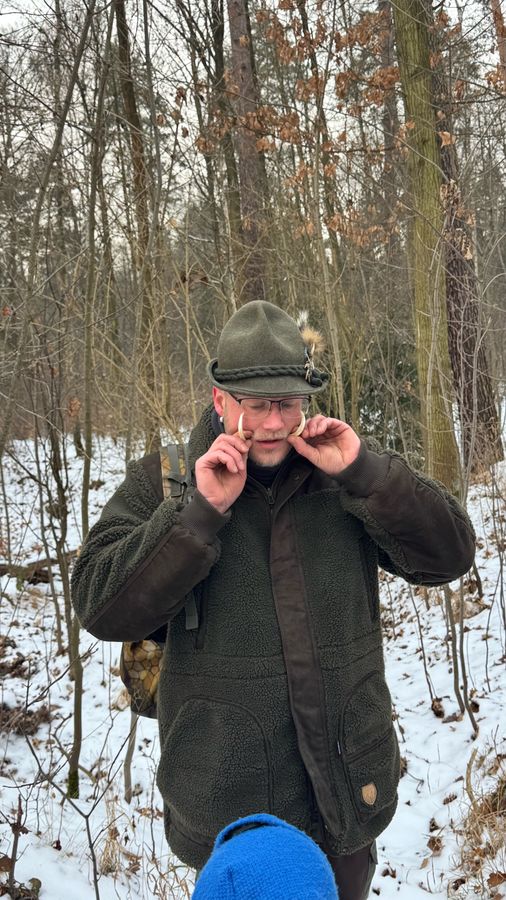 Jäger im Wald mit Wildschweinzähnen in der Hand