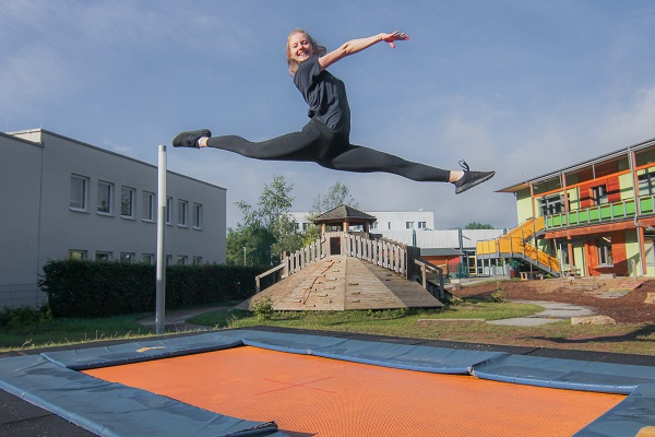 pädagogische Fachkraft des Kindergarten Sportforum in Jena eine pädagogische Fachkraft der Kita Sportforum springt auf dem Boden-Trampolin im Garten der Kita