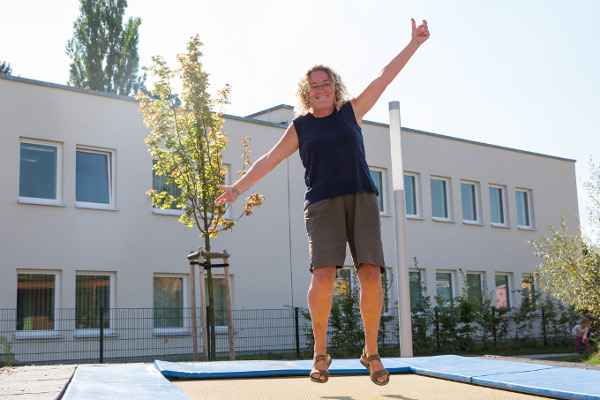 pädagogsiche Fachkraft des Kindergarten Sportforum in Jena eine pädagogische Fachkraft der Kita Sportforum springt auf dem Boden-Trampolin im Garten der Kita