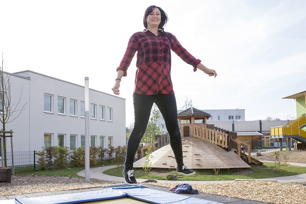 pädagogische Fachkraft des Kindergarten Sportforum in Jena eine pädagogische Fachkraft der Kita Sportforum springt auf dem Boden-Trampolin im Garten der Kita